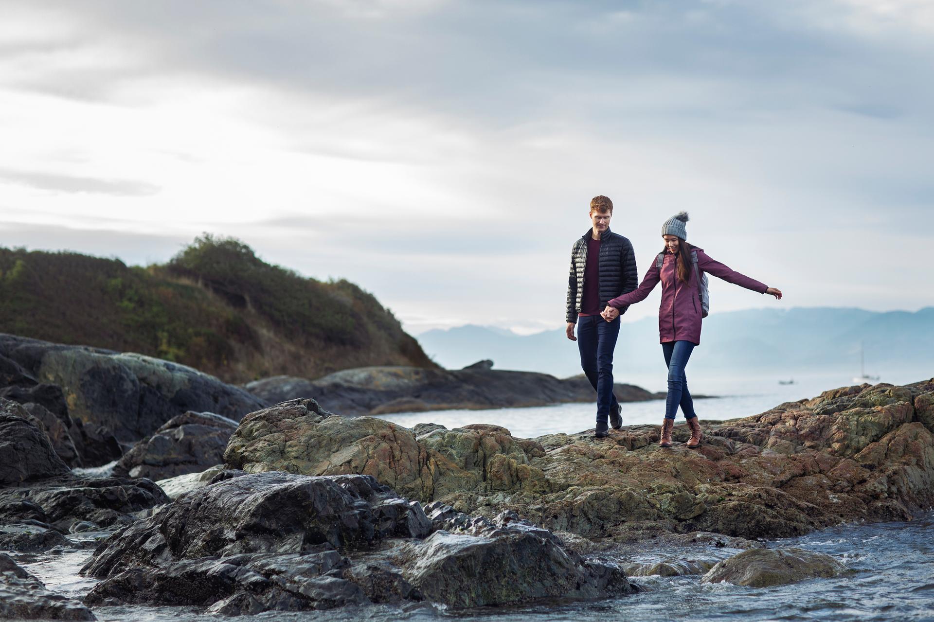 a young couple walking along the shoreline in Victoria, BC