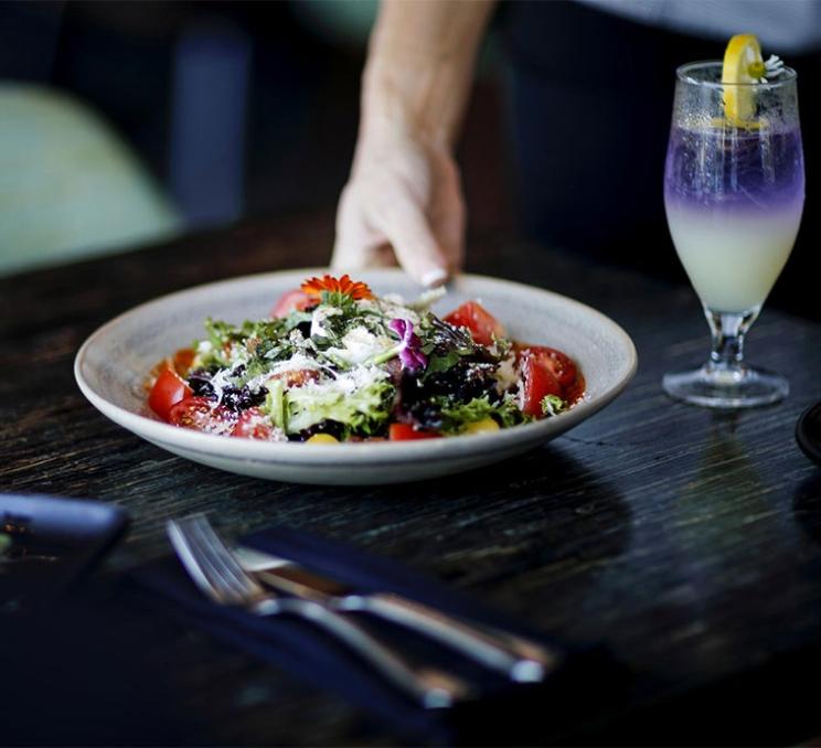 A plate of food is served next to a cocktail.