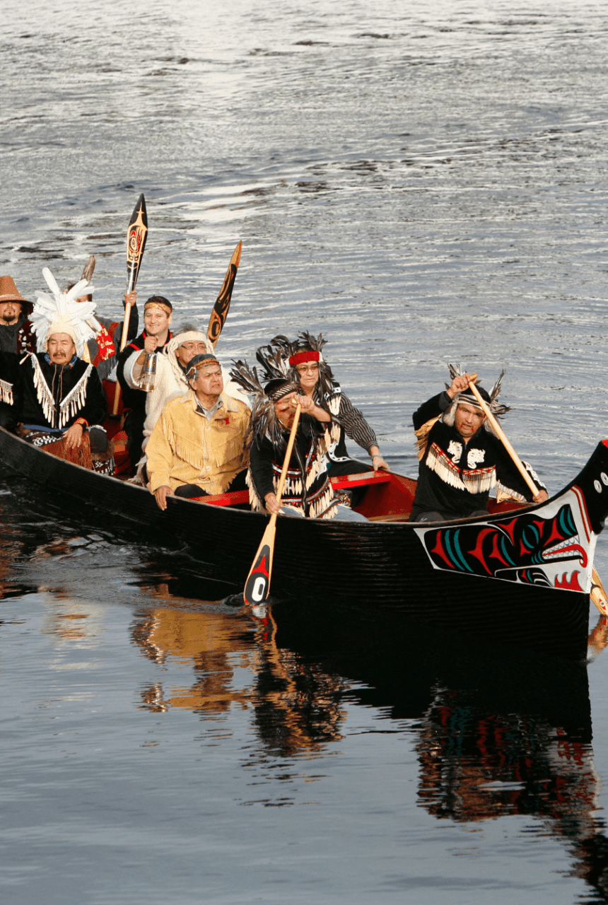 A group of Indigenous people paddling in a canoe in Victoria, BC