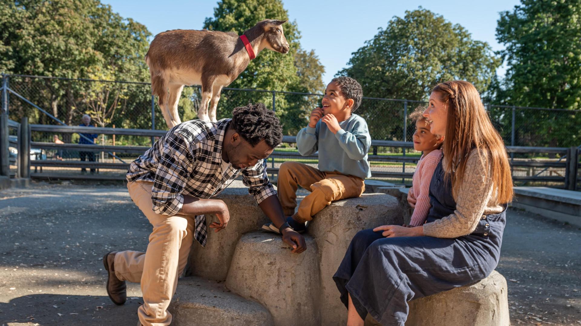 a smiling family enjoying the petting zoo at Beacon Hill Park