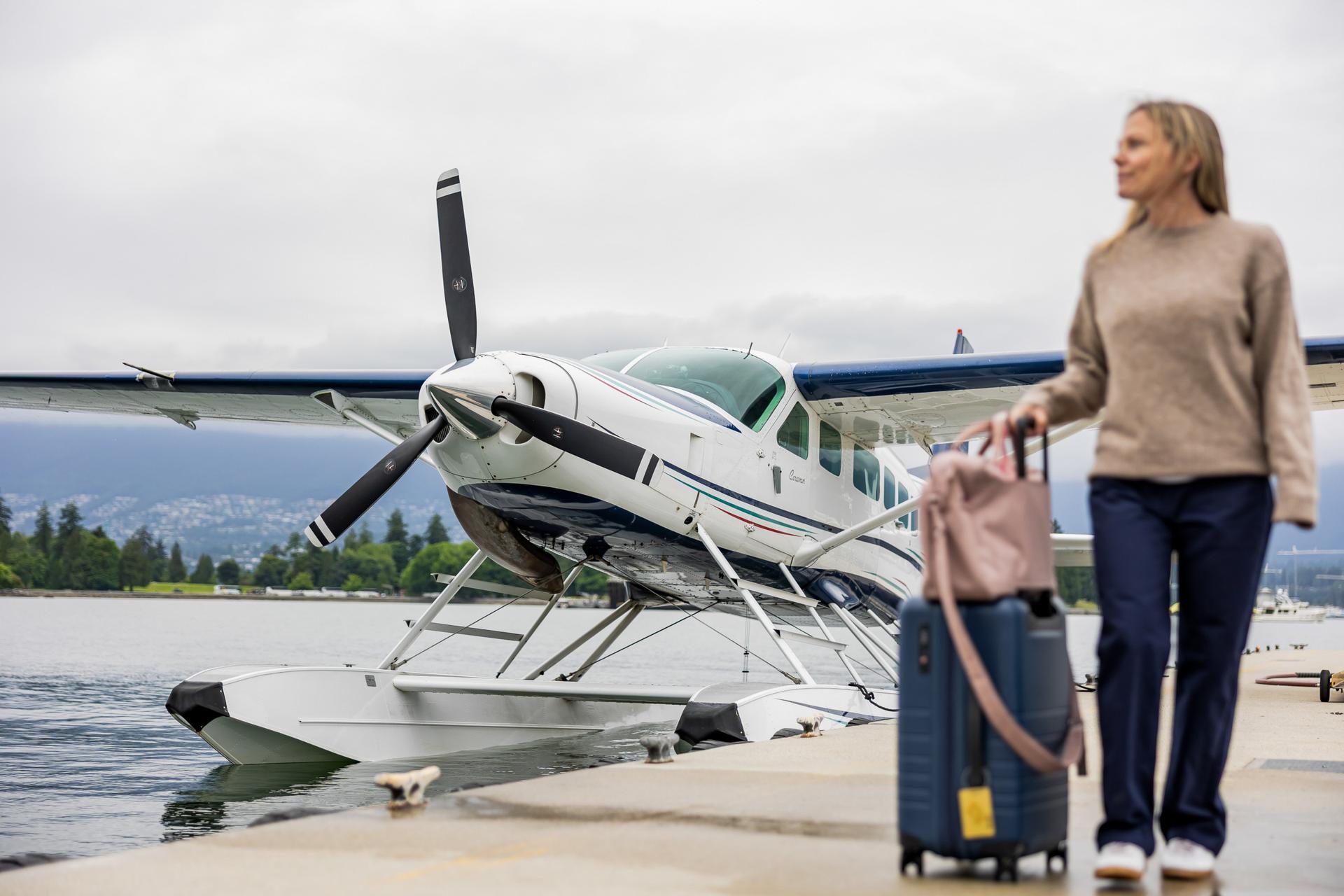 Passenger with luggage in front of caravan.